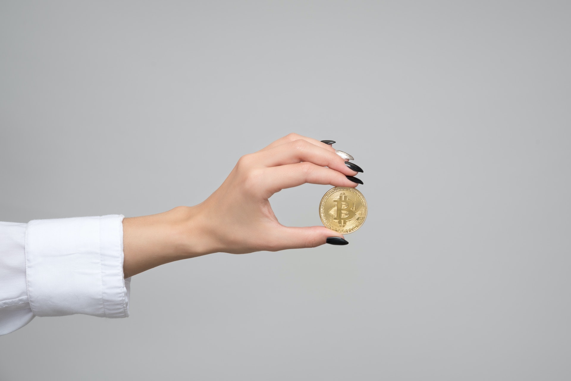 manicured hand holding bitcoin